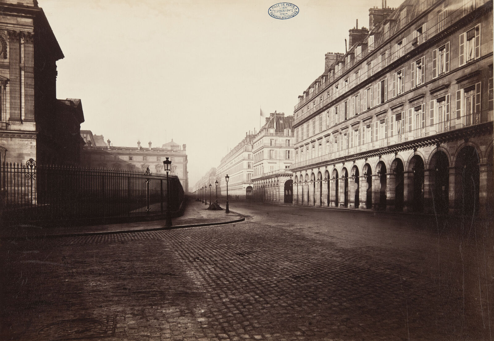 Für diese Aufnahme bezog der Photograph seinen Standort ganz in der Nähe des Louvre. Der niedrige Kamerastandpunkt betont dabei den weiten Straßenraum.
