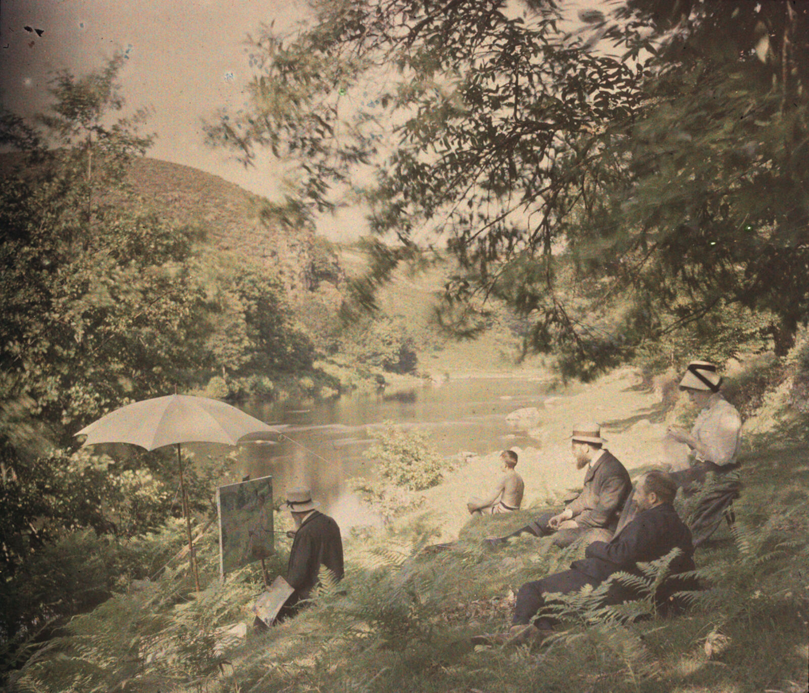 Um 1907 photographierte Antonin Personnaz den Impressionisten Armand Guillaumin beim Malen. Die körnige Bildstruktur des Autochroms verstärkt die impressionistische Wirkung dieser sommerlichen Flusslandschaft; die Figurenkomposition spielt dabei auf ein berühmtes Gemälde des Pointillisten Georges Seurat an.